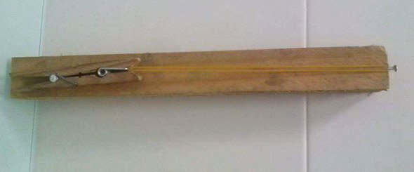 Ballesta casera hecha con un palo de madera y una pinza.