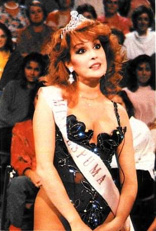 Mujer con corona y banda de miss ante el público de un plató