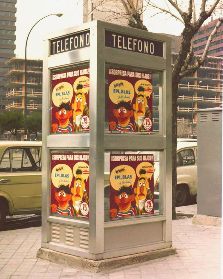 Cabina de teléfono de Telefónica en una acera con carteles