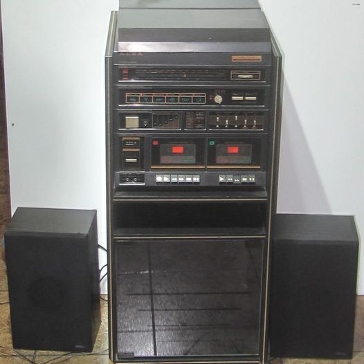 Cadena de música con mueble de cristal y dos altavoces.
