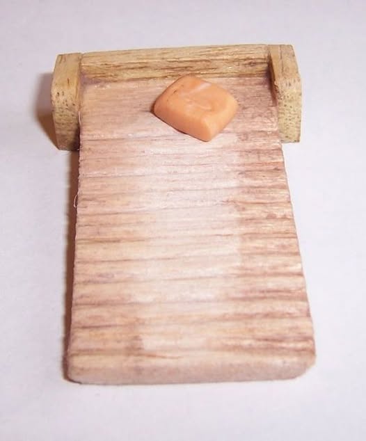Cama de muñecas de madera con una almohada