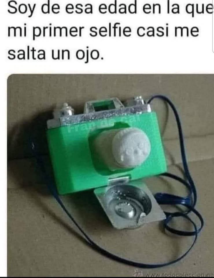 Cámara de fotos de juguete verde con un muñeco blanco saliendo del objetivo y un cordón azul.