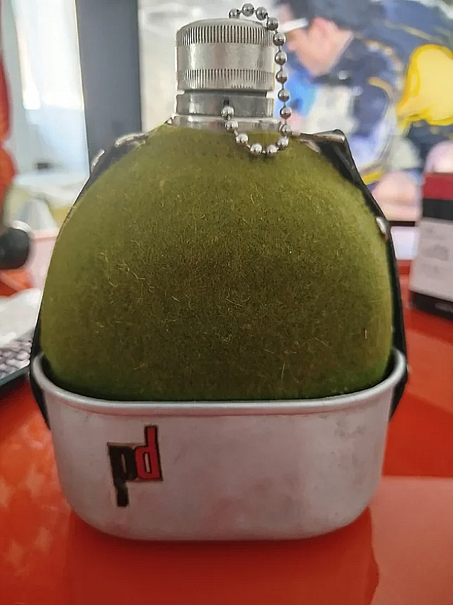 Cantimplora forrada de fieltro verde con su vaso metálico.