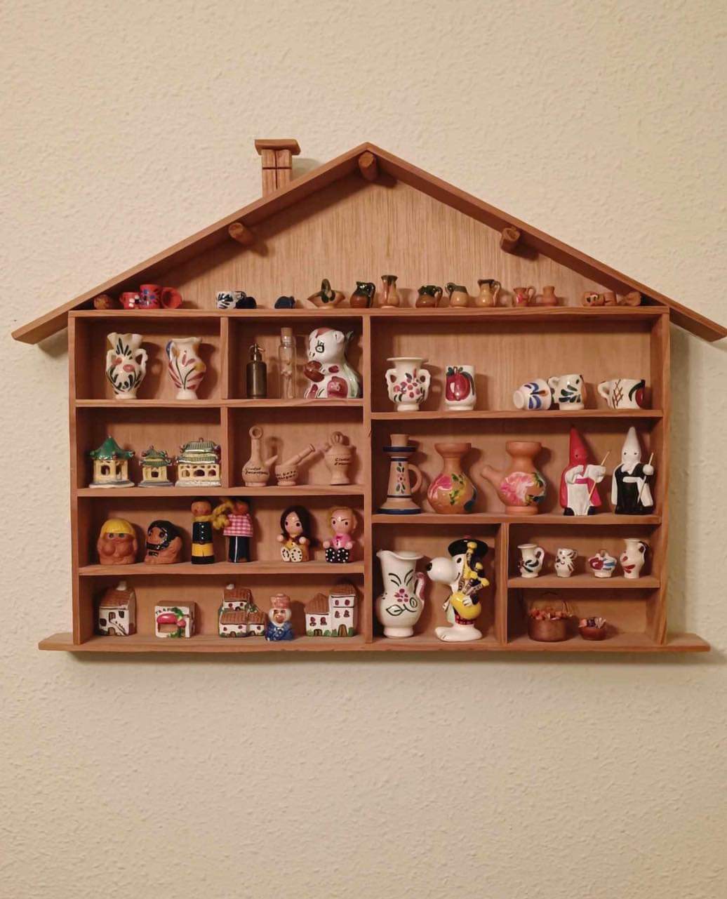 Estantería de madera con forma de casa llena de miniaturas