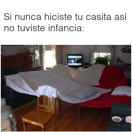 Sábana extendida entre una silla y un sofá rojo formando una cabaña en un salón.
