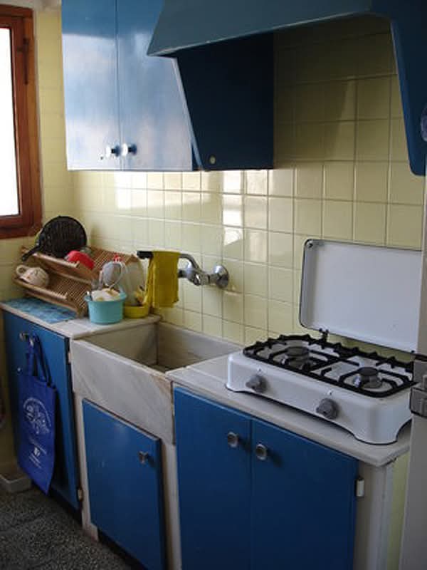 Cocina antigua con muebles azules, fregadero y hornillo de gas