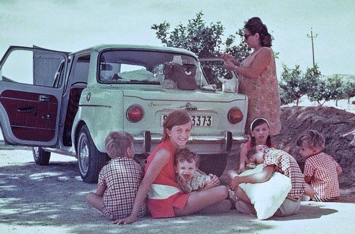 Familia comiendo en el campo junto a un coche con las puertas abiertas