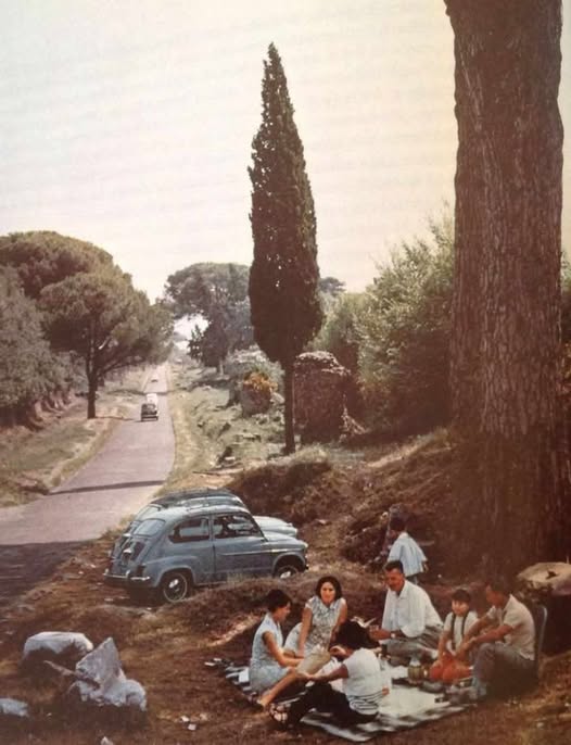 Familia comiendo en el campo junto a un coche aparcado