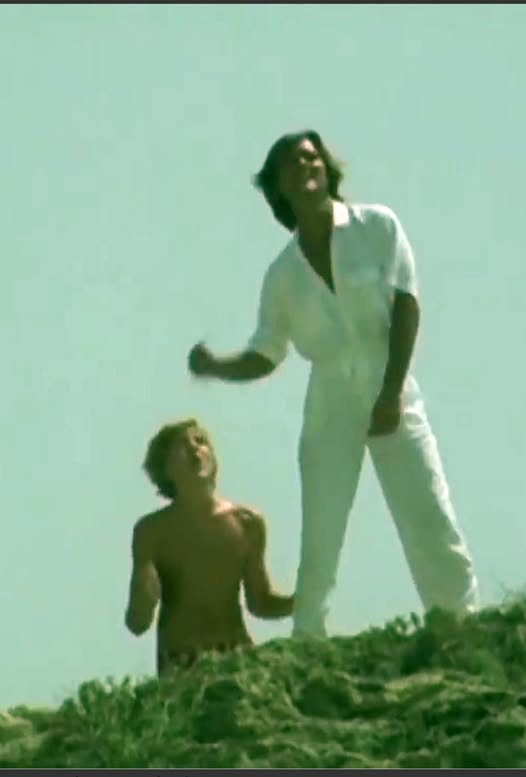 Hombre vestido de blanco y un niño en lo alto de una colina