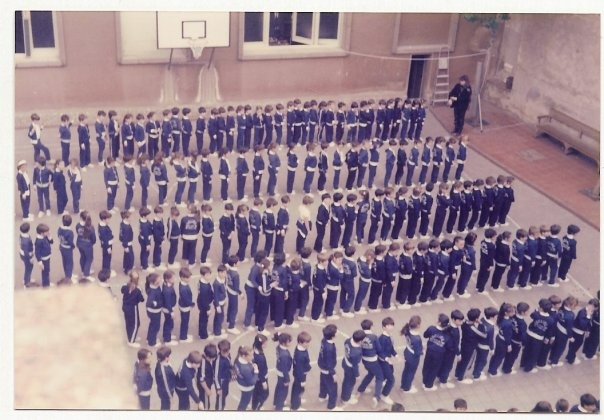Alumnos uniformados formando en filas en el patio de un colegio