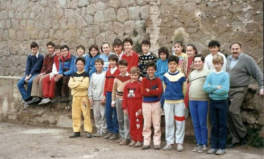 Grupo de niños y adultos posando junto a un muro de piedra