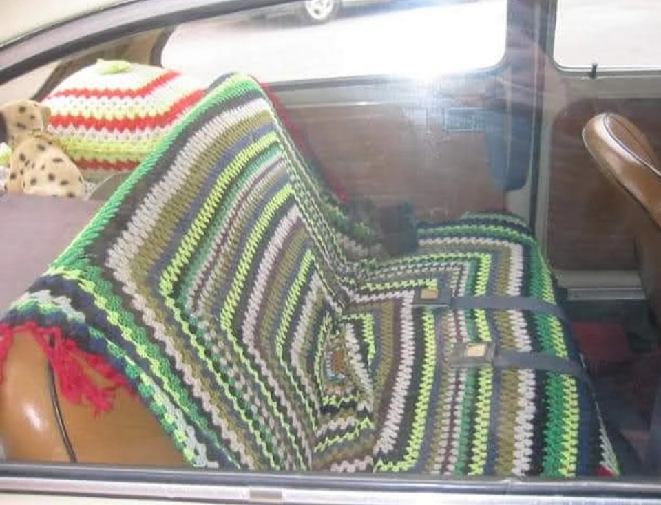 Asiento trasero de coche cubierto con una manta de ganchillo.