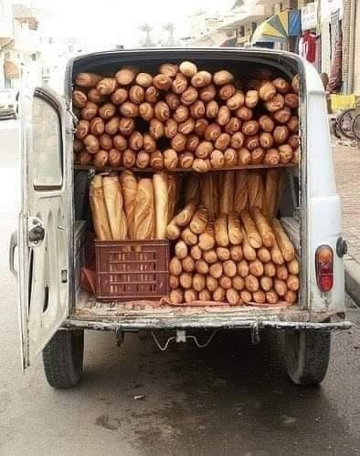 Furgoneta blanca con las puertas de atrás abiertas, llena de barras de pan y panecillos.