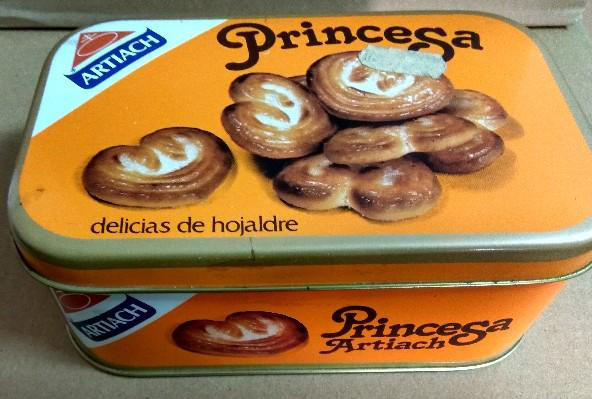 Lata naranja de galletas Princesa de Artiach con palmeritas de hojaldre dibujadas.