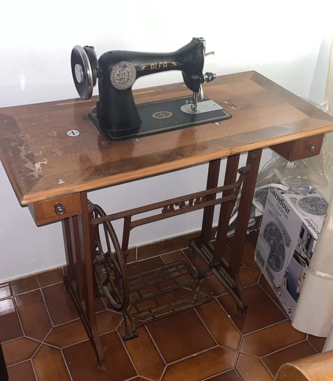 Máquina de coser antigua de pedal sobre un mueble de madera