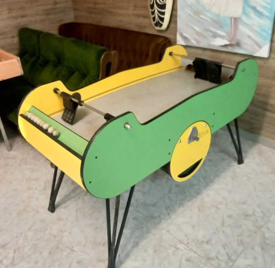 Mesa de juego de madera verde y amarilla con palas.