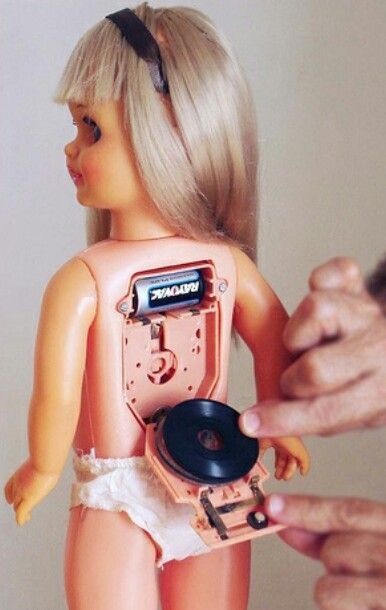 Muñeca rubia con un tocadiscos en la espalda.