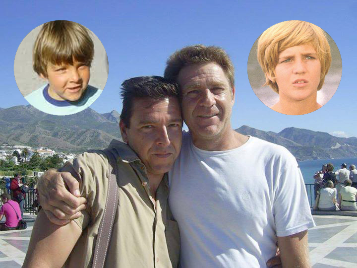Dos hombres abrazados en un mirador junto a sus fotos de niños