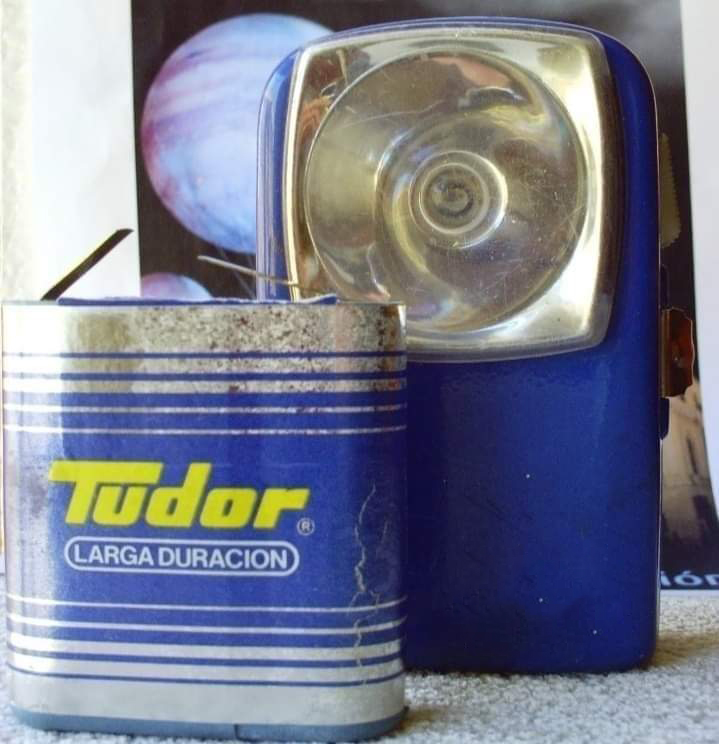 Pila de petaca Tudor junto a una linterna.