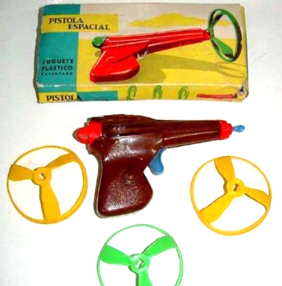 Pistola de juguete roja con hélices de plástico de colores y su caja.