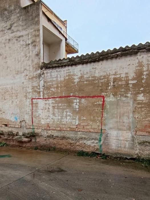 Portería pintada con pintura roja en una tapia de ladrillo.