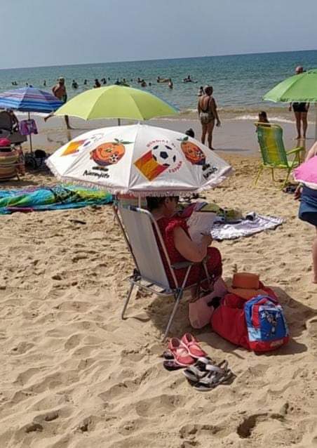 Sombrilla con Naranjito del Mundial 82 en una playa con gente.