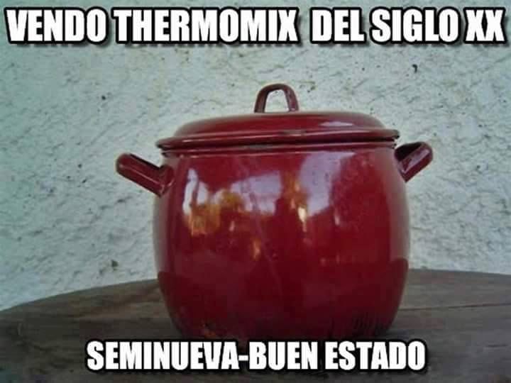 Olla de porcelana esmaltada roja con tapa y dos asas sobre una mesa de madera.