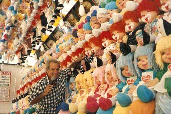 Feriante con micrófono en una tómbola llena de muñecos de peluche
