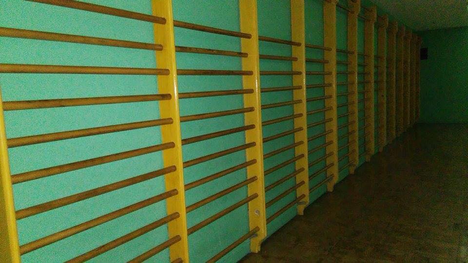 Espalderas de madera amarillas en un gimnasio verde.