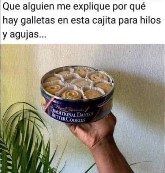 Mano sujetando una lata redonda de galletas danesas de mantequilla abierta y llena de galletas.