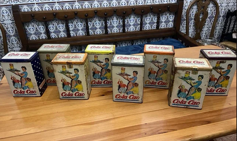 Varias latas antiguas de Cola Cao en fila.