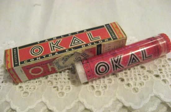 Caja y tubo rojos de pastillas Okal sobre un tapete de ganchillo.
