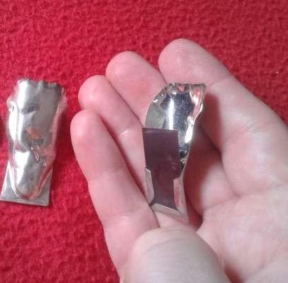 Mano con dos ranitas de chapa que hacen ruido al apretarlas.