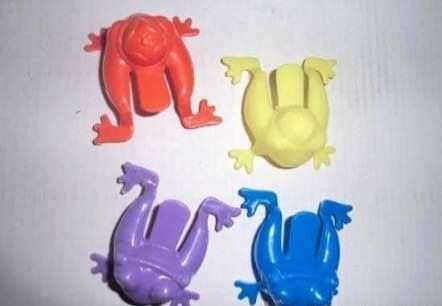 Cuatro ranitas saltarinas de plástico de colores rojo, amarillo, morado y azul.