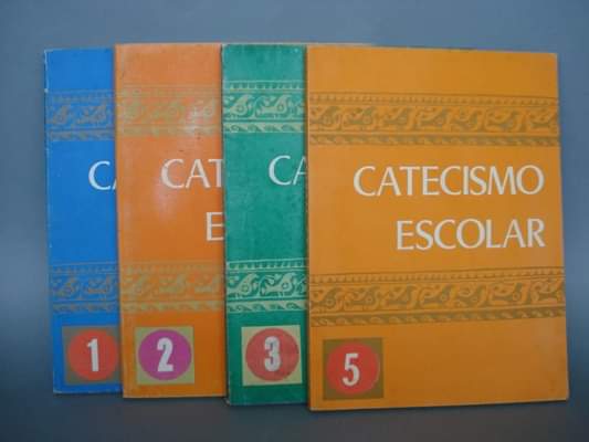 Cuatro libros de Catecismo Escolar numerados, de colores azul, naranja, verde y amarillo.