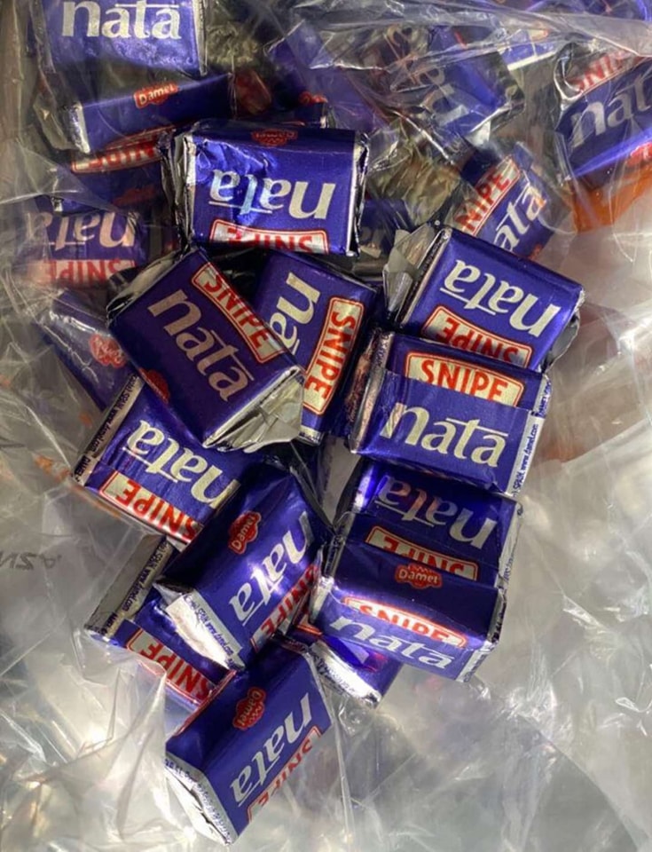 Montón de caramelos de nata Snipe envueltos en papel morado dentro de una bolsa de plástico.