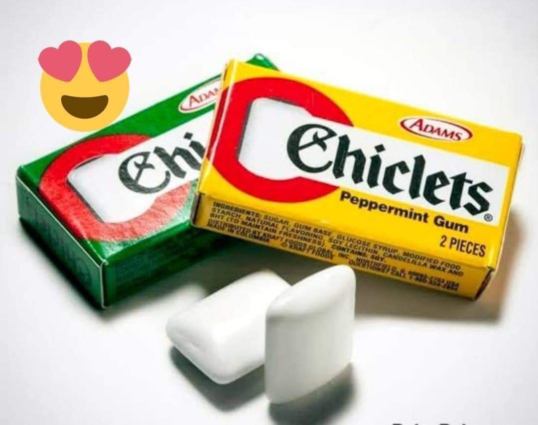 Dos cajitas de chicles Chiclets, una verde y otra amarilla, con dos chicles blancos delante.