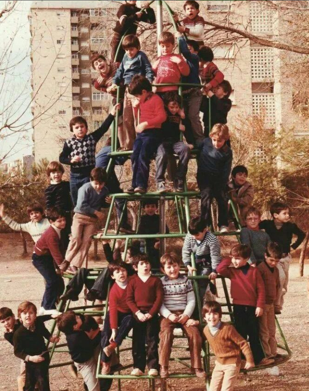 Muchos niños subidos a una estructura de juegos de hierro en un parque