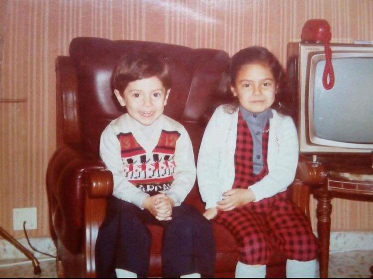 Dos niños sentados en un sillón junto a un televisor