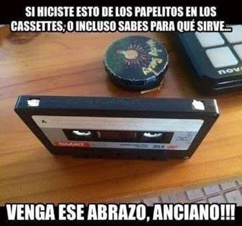 Casete sobre una mesa de madera con papelitos blancos encajados en los dos huecos de la parte superior.