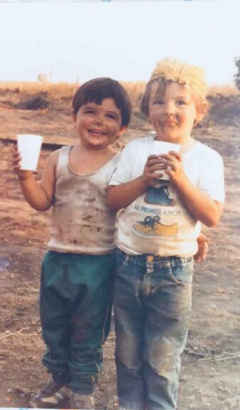 Dos niños sonrientes con vasos de plástico en el campo