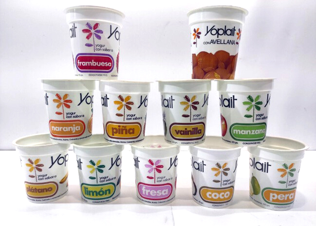 Pirámide de envases antiguos de yogur Yoplait de distintos sabores con una flor de colores.