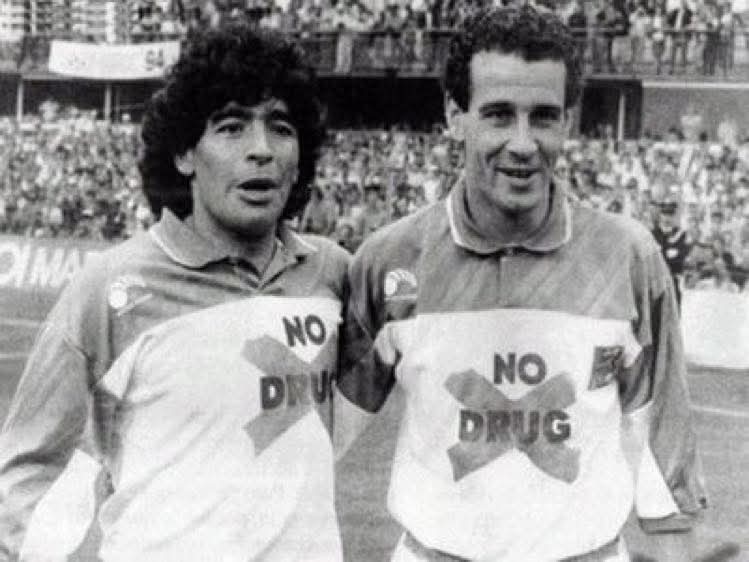 Maradona y Julio Alberto con camisetas de No drug en un estadio