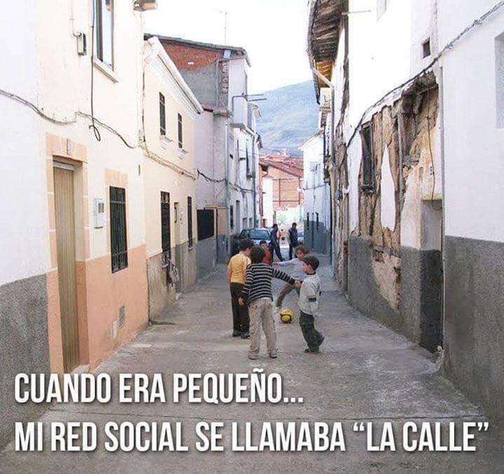 Niños jugando con un balón en una calle estrecha de un pueblo con casas encaladas.