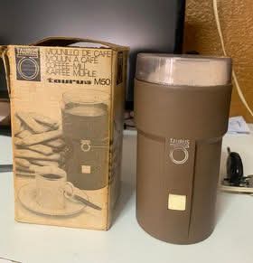 Molinillo de café eléctrico Taurus marrón junto a su caja.