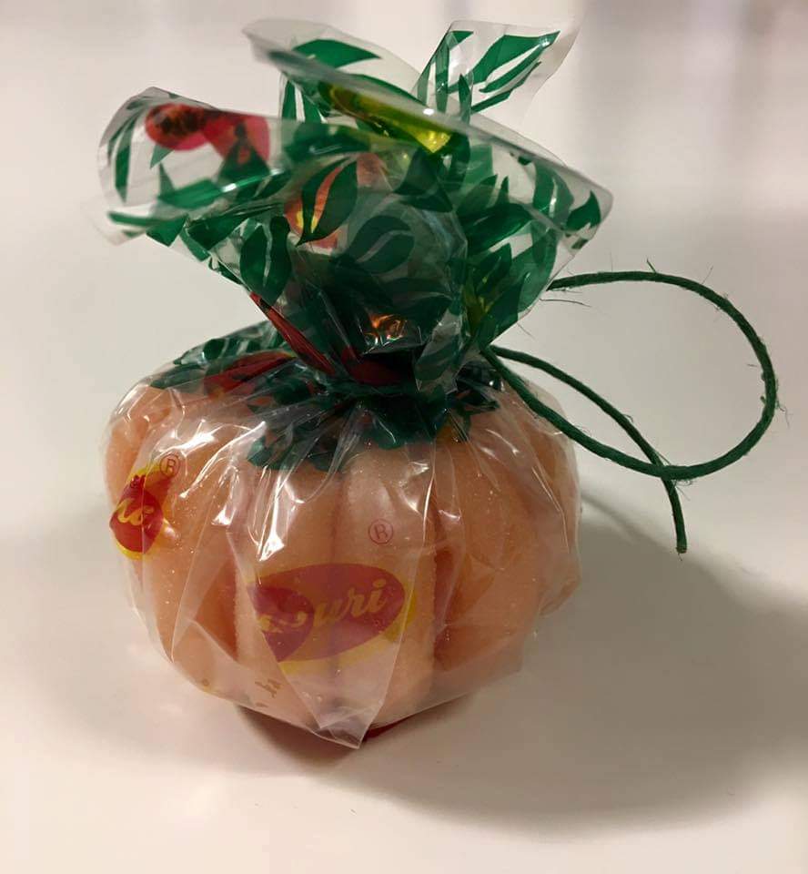 Caramelo con forma de naranja envuelto en celofán con lazo verde.