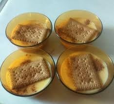 Cuatro cuencos de cristal ámbar con natillas, una galleta y canela.