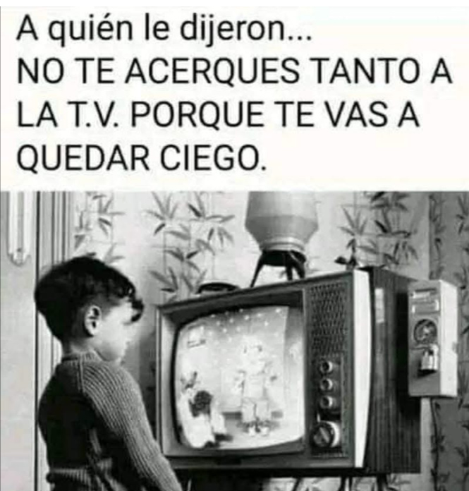 Foto en blanco y negro de un niño de pie muy cerca de un televisor antiguo.