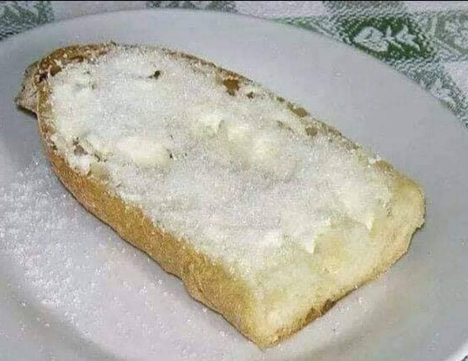 Rebanada de pan con mantequilla y azúcar en un plato.