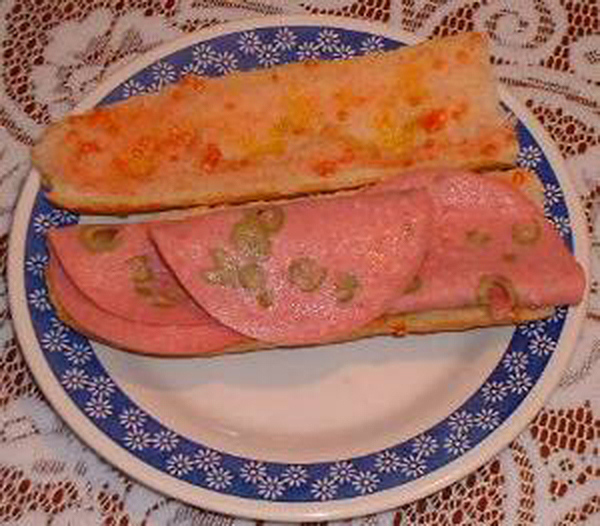 Plato con pan con tomate y lonchas de mortadela con aceitunas.